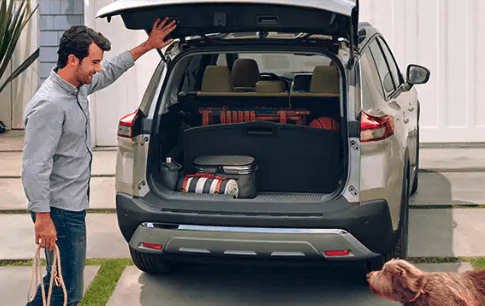 Man standing next to a Nissan Rogue with an open trunk.