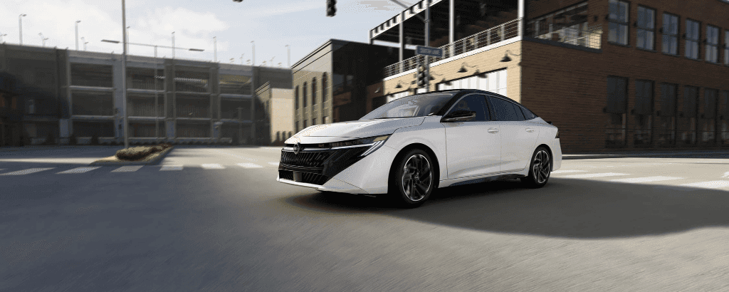 A white 2026 Nissan Sentra driving through an intersection.