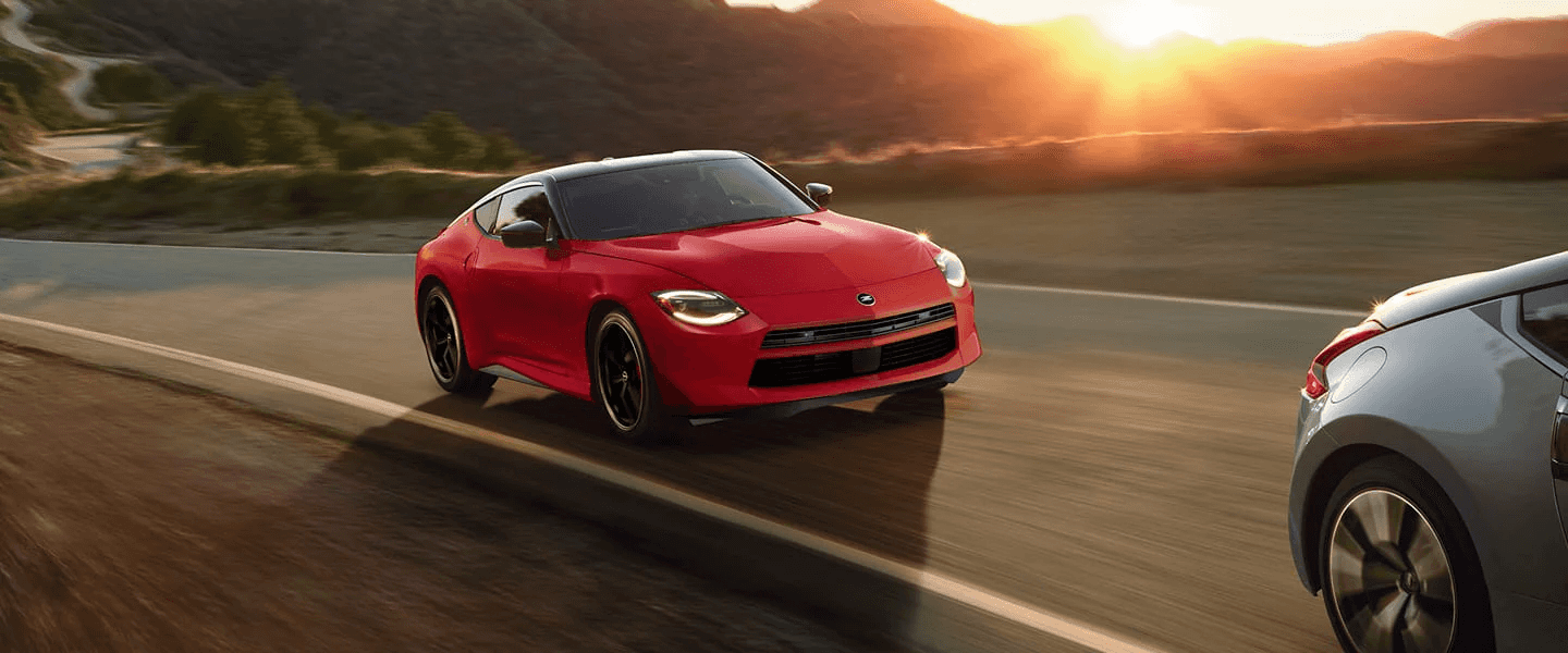 A red Nissan Z following a silver vehicle on the highway.