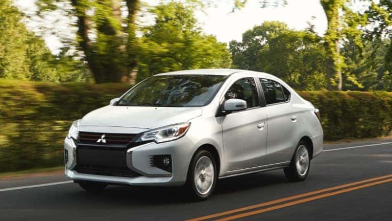 2021 Mitsubishi Mirage White exterior driving through green hedges