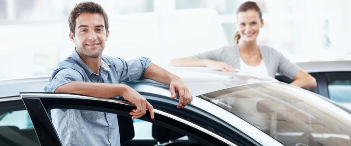Two people standing inside a car's open front doors