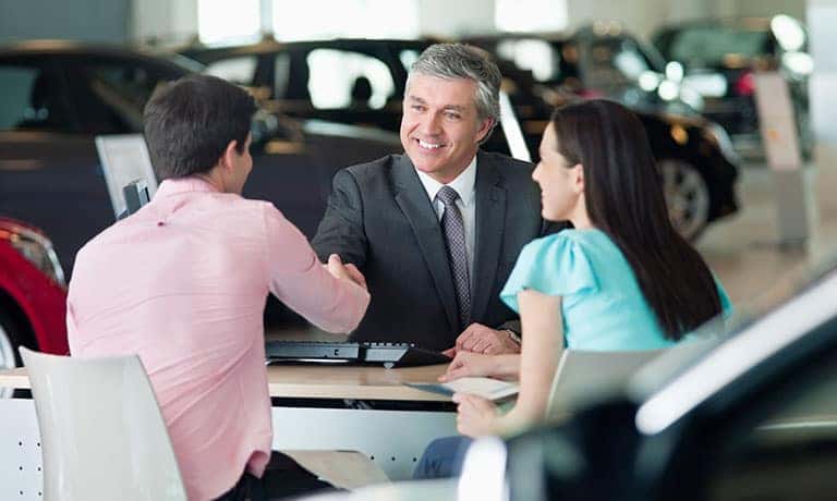Couple making deal with car salesman