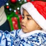 Young boy in Santa hat helping with Christmas