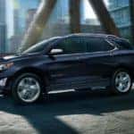 A blue 2021 Chevy Equinox driving on an iron city bridge.