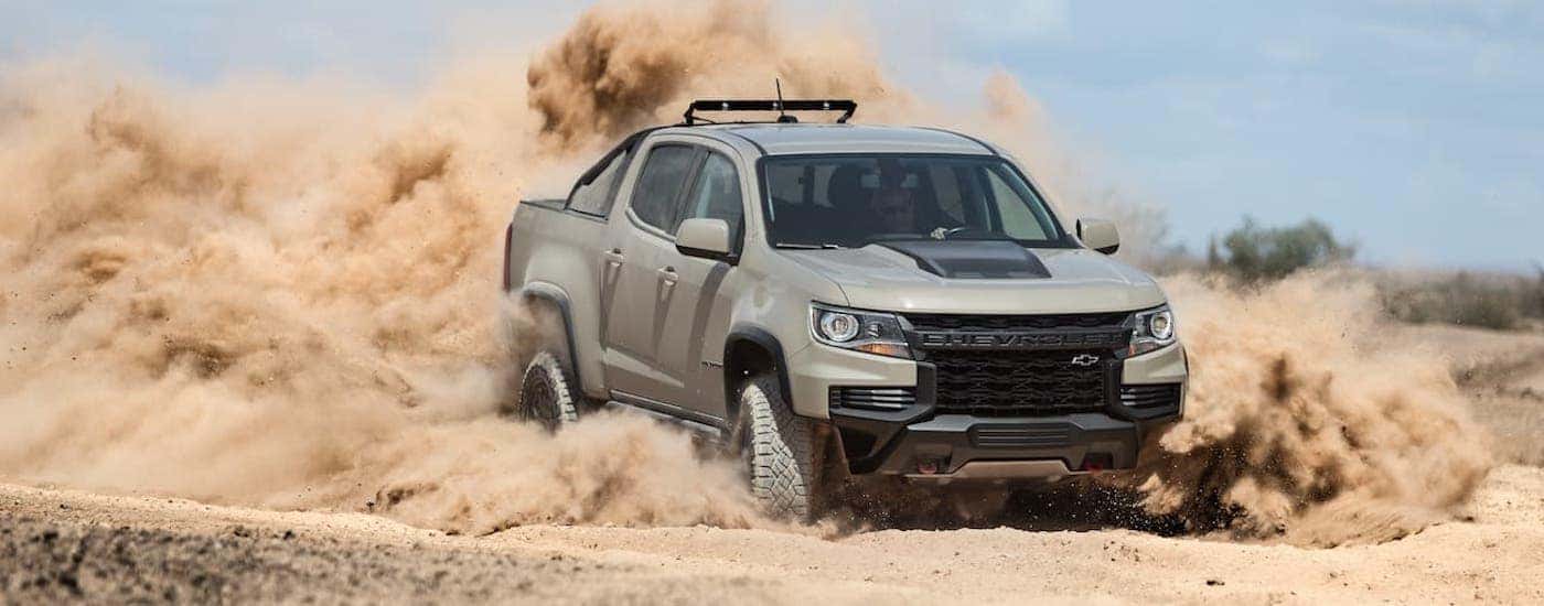 A tan 2021 Chevy Colorado ZR2 is driving through a desert.