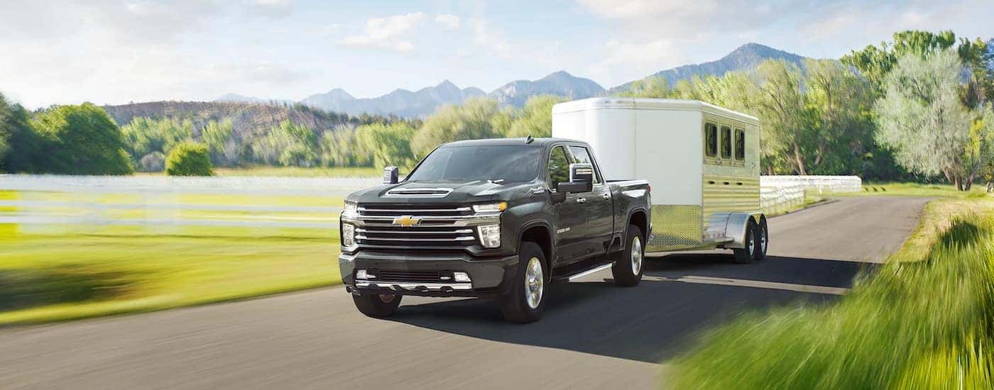 A black 2022 Chevy Silverado 3500 HD is shown towing a horse trailer. 