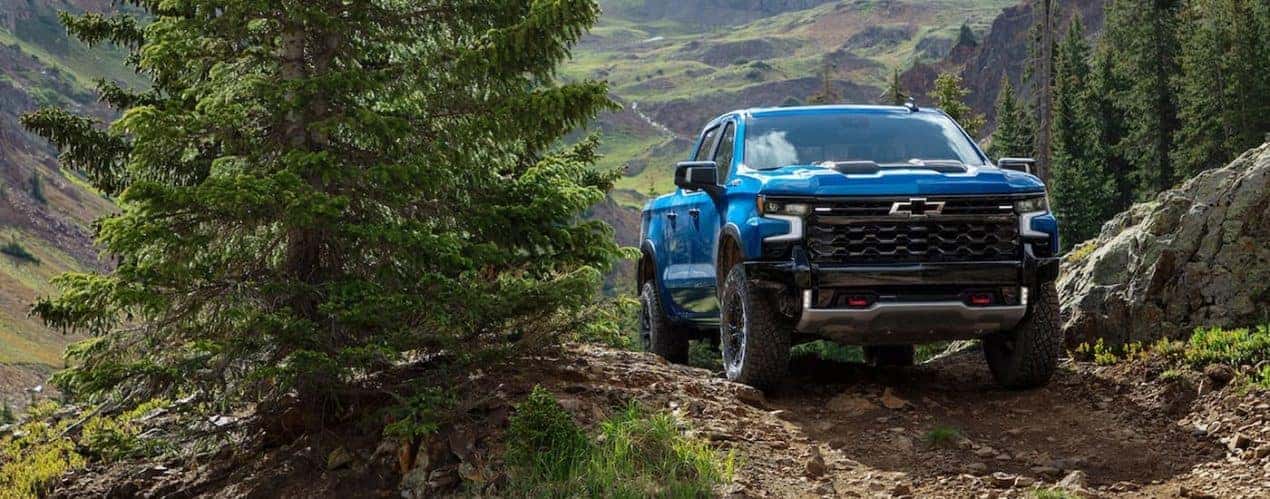 A blue 2022 Chevy Silverado 1500 ZR2 is shown driving up a mountain trail.