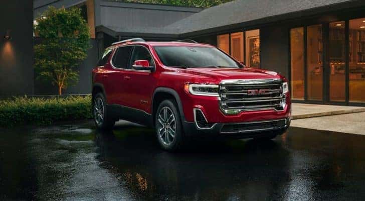 A red 2020 GMC Acadia from a used GMC dealer is shown parked outside of a modern home.