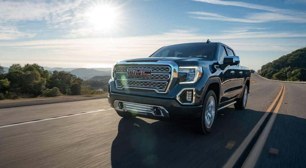 A grey 2020 GMC Sierra 1500 Denali driving on a highway in the mountains.