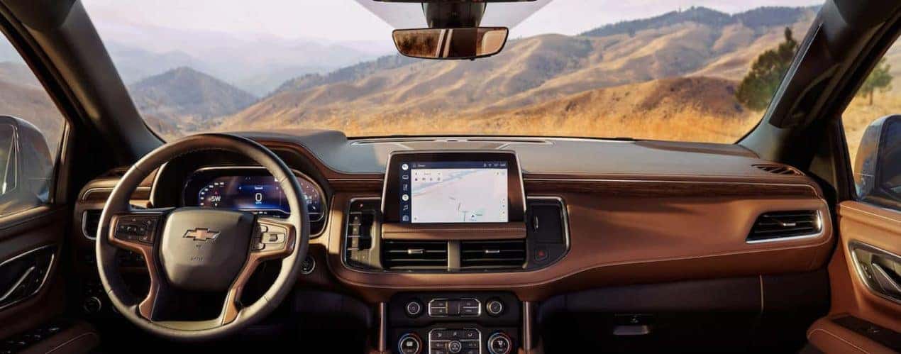 The tan interior of a 2022 Chevy Tahoe shows the steering wheel and infotainment screen.