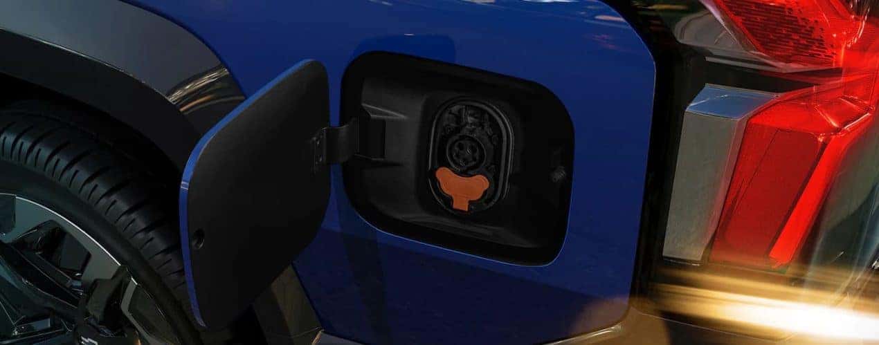A close up shows the charge port on a blue 2024 Chevy Silverado EV.