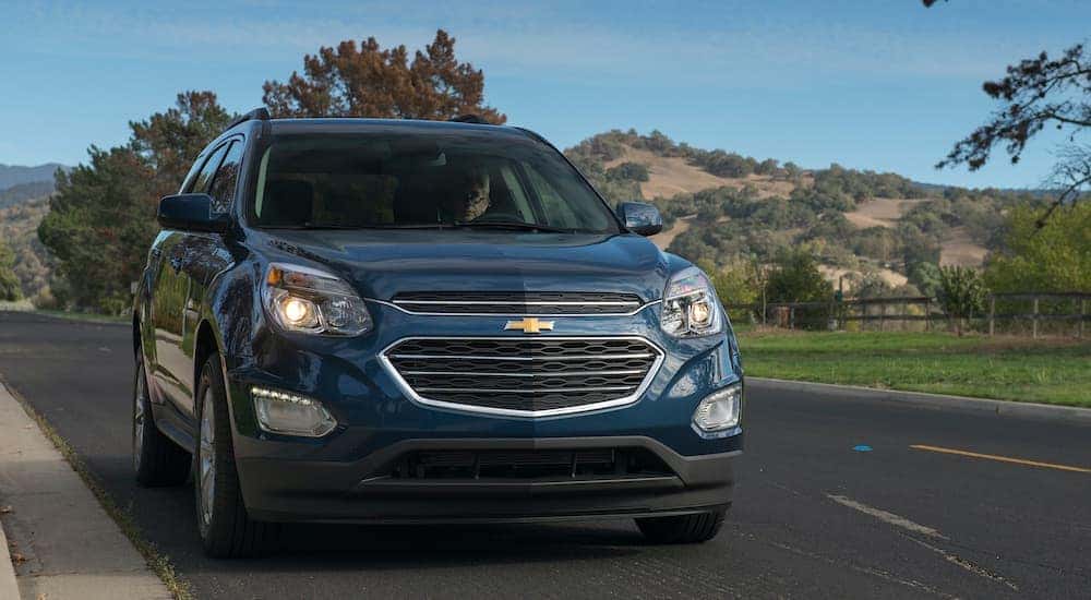 A blue 2016 Chevy Equinox LT driving on open country road.