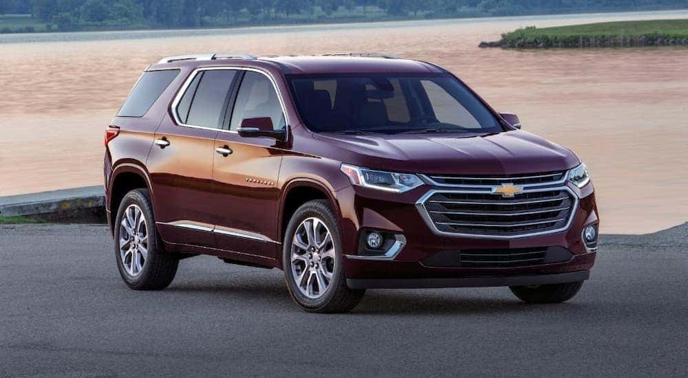A maroon 2018 Chevy Traverse parked in front of a body of water.