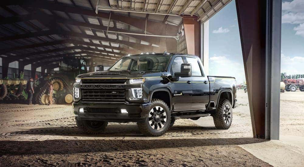 A black 2021 Chevy Silverado 2500 HD Carhartt Edition parked in a barn with farm equipment.