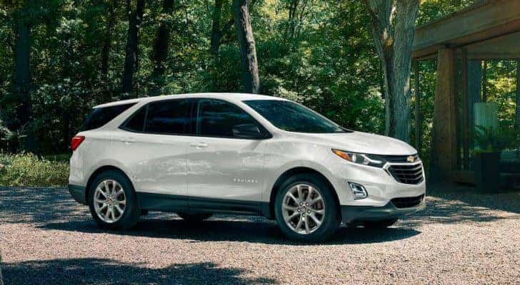One of the most popular used SUVs for sale, a white 2020 Chevy Equinox, is shown on a gravel driveway.