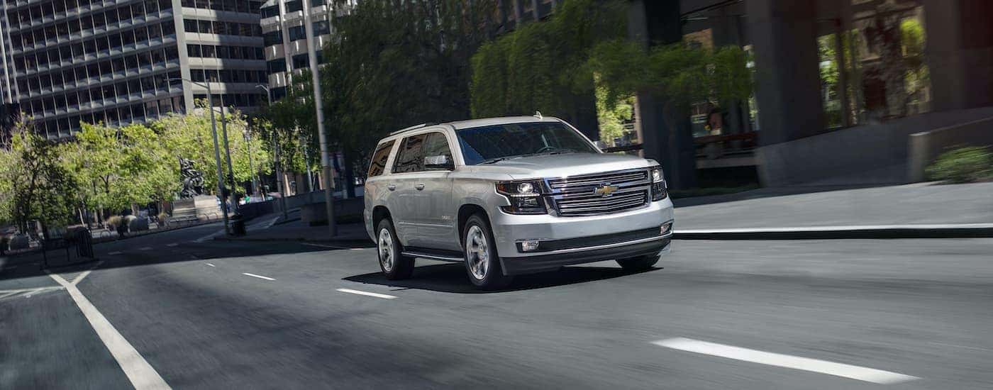 A silver 2020 Chevy Tahoe Premier Plus is shown driving on a city street.