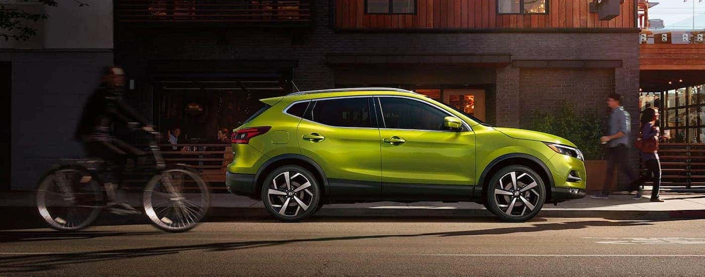 A green 2021 Nissan Rogue Sport is shown on a city street.