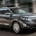 A grey 2019 Chevy Equinox driving on a blurred city street.