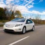 A white 2015 Chevy Volt is shown from the front driving on an open road.