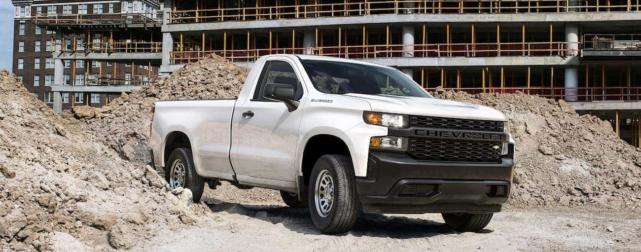 A white 2020 Chevy Silverado 1500 WT is shown driving through a construction site.