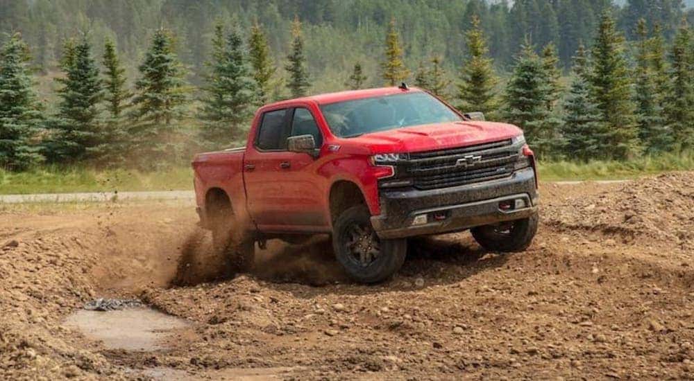 A red 2020 Chevy Silverado 1500 kicks up dust in a dirt pit while off-roading