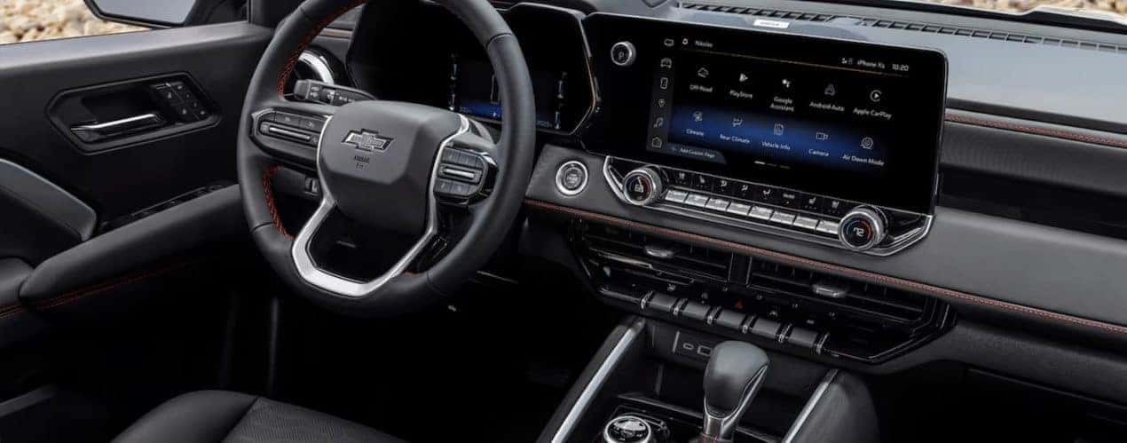 The interior of a black 2023 Chevy Colorado shows the steering wheel and center console.