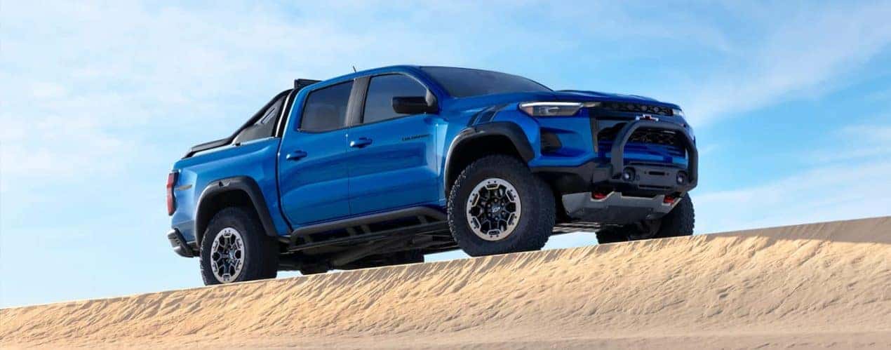 A blue 2023 Chevy Colorado ZR2 is shown parked on a sandy dune.