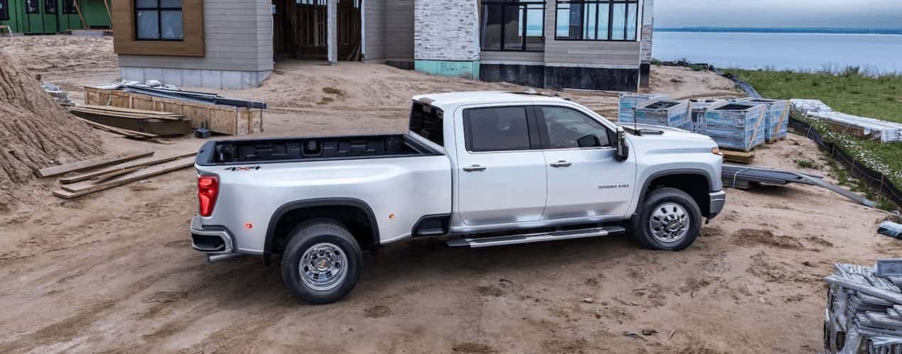 A white 2024 Chevy Silverado 3500 HD is shown from the side parked at a construction site.