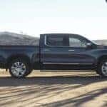 A man loads a saddle into the bed of his black 2024 Chevy Silverado 1500 High Country