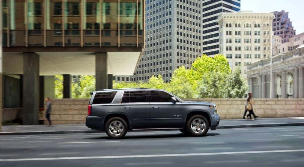 A silver 2020 Chevy Tahoe Premier Plus driving on a city street after leaving a Huntsville used Chevy dealer.