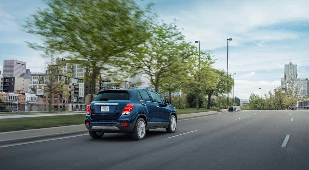 A blue 2020 Chevy Trax driving on an empty city street.