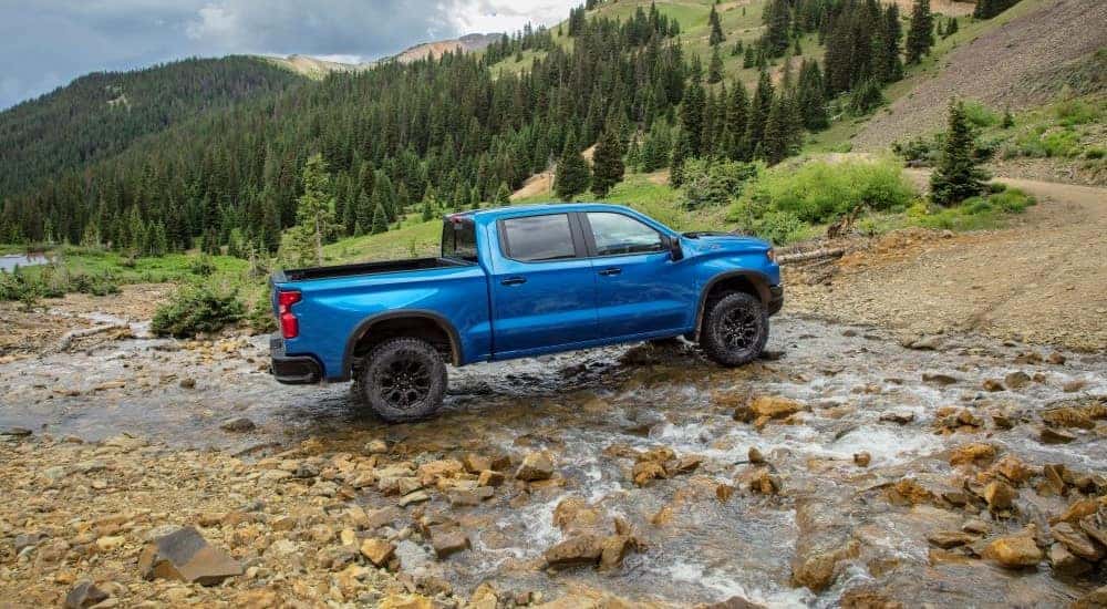 A blue 2022 Chevy Silverado ZR2 off-roading through a rocky creek