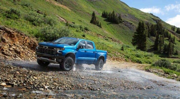 A blue 2022 Chevy Silverado ZR2 is driving through a creek after leaving a Huntsville used Chevy dealer.