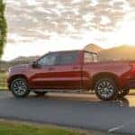A red 2020 Chevy Silverado 1500 Z71 driving past a horse paddock on a sunny day.