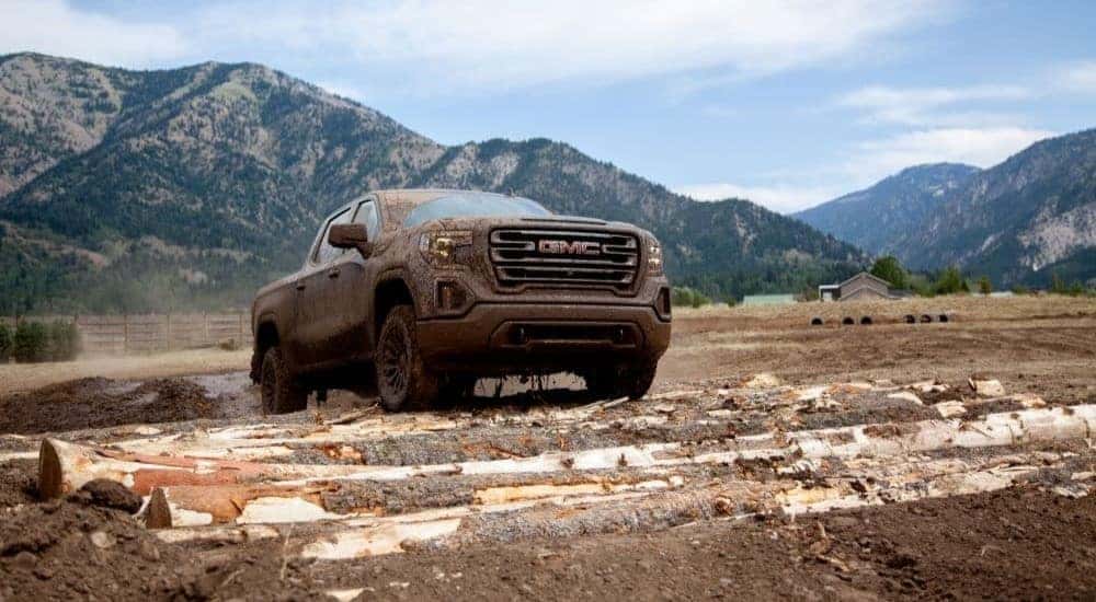Covered in mud, a black 2020 GMC Sierra 1500 AT4 off-roads through a wet field