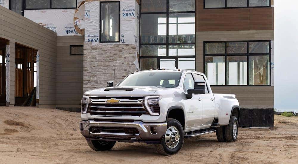 A white 2024 Chevy Silverado 3500 HD LTZ parked in front of a modern construction site