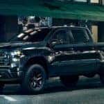 A black 2023 Chevy Silverado 1500 Z71 Trail Boss parked on a dimly lit city street