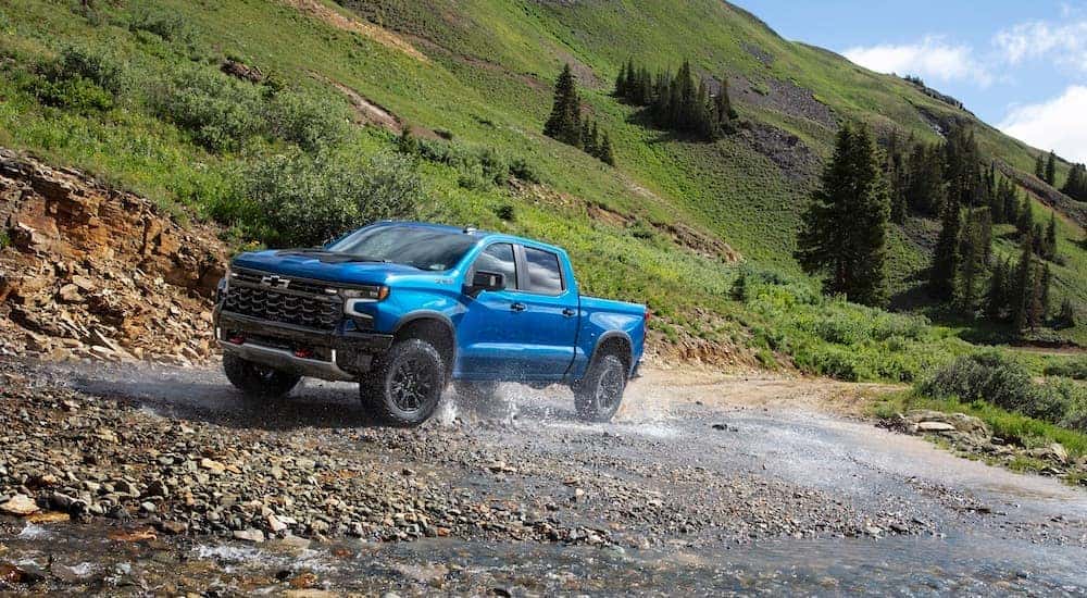 A blue 2024 Chevy Silverado 1500 ZR2 is shown from the front at an angle during a 2024 Chevy Silverado 1500 vs 2024 Ford F-150 comparison.