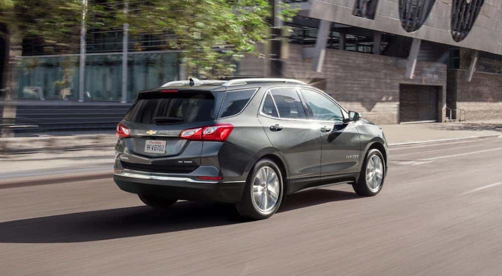 A grey 2021 Chevy Equinox is shown driving in a city.