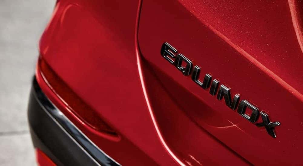 A close-up on a Equinox badge is shown on a red 2024 Chevy Equinox.