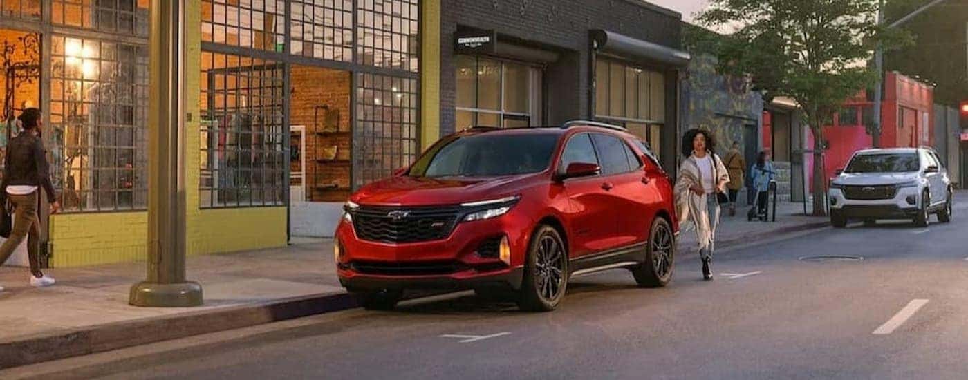 A red 2024 Chevy Equinox RS is shown parked near buildings.