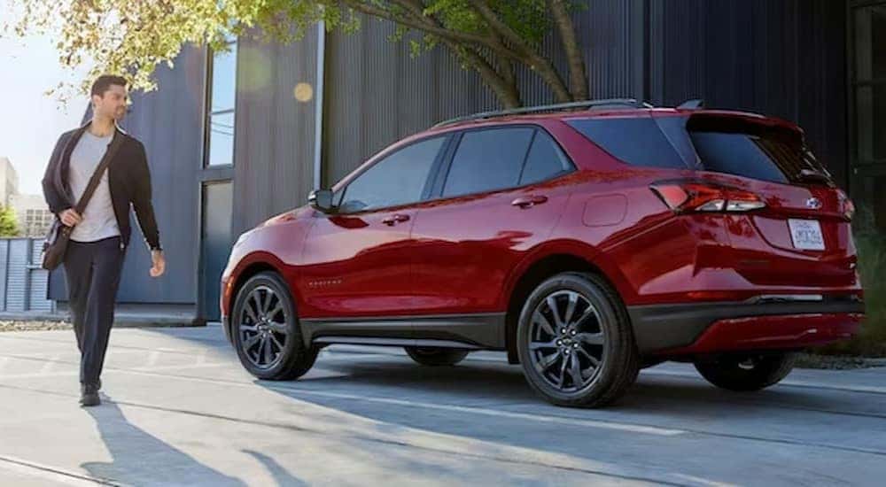 A person is shown walking near a red 2024 Chevy Equinox RS.
