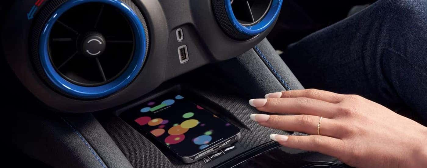 A hand is shown placing a phone on a wireless charger in a 2024 Chevy Blazer.