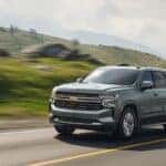 A silver 2024 Chevy Tahoe driving on an open country road.