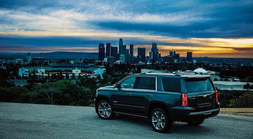 A black 2024 Chevy Tahoe overlooking a city skyline at dusk.