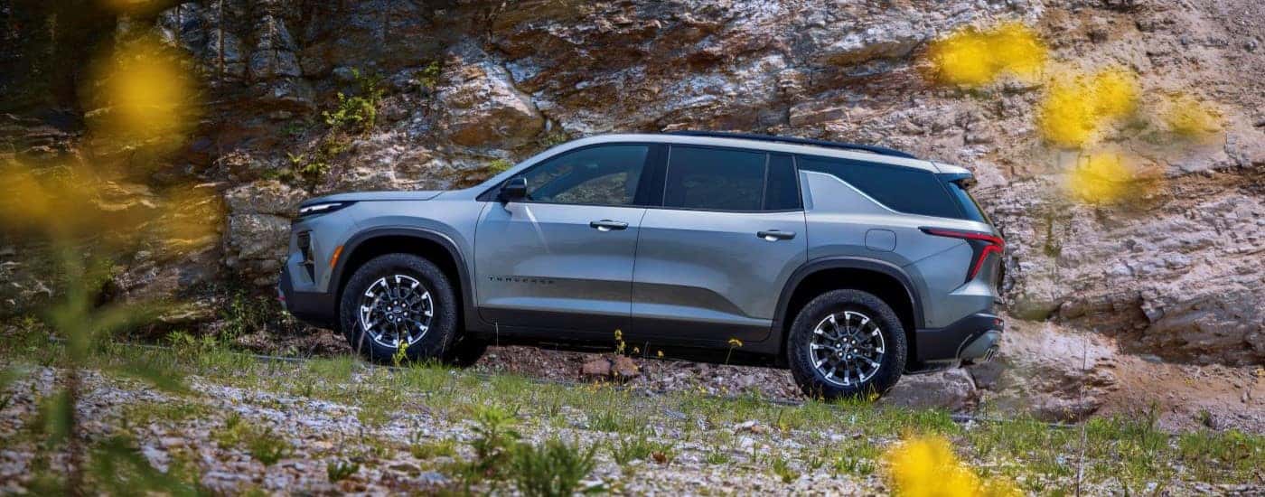 A silver 2024 Chevy Traverse Z71 is shown from a side angle while parked off-road.
