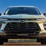 One of many popular Chevy SUVs for sale, a green 2024 Chevy Trax, is shown parked near water.