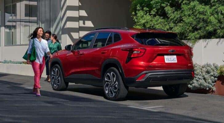 A person is shown walking away from one of the most common Chevy SUVs for sale, a red 2024 Chevy Trax.