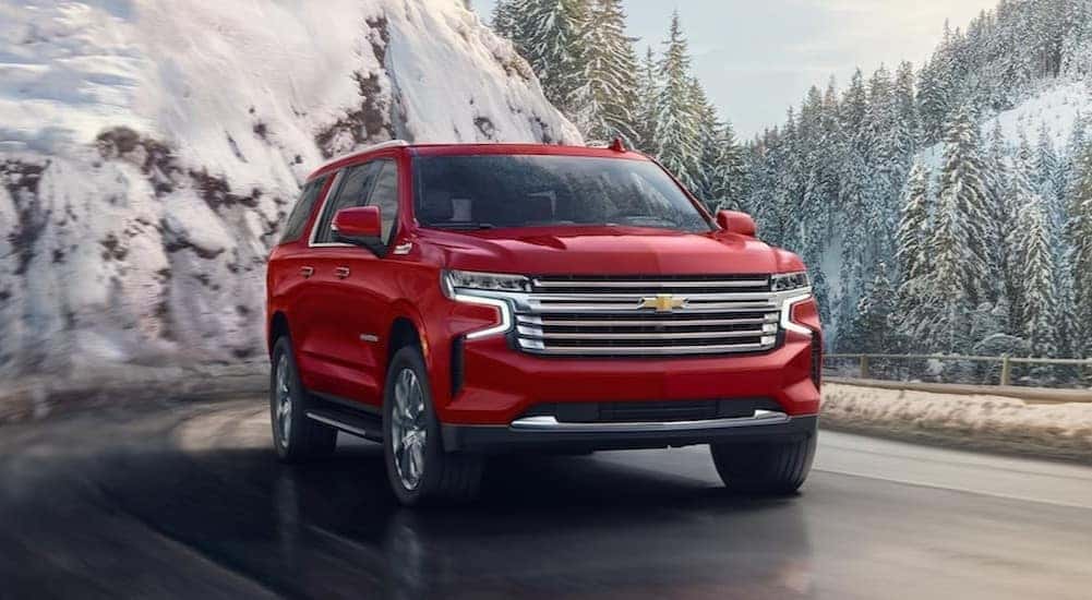 A red 2024 Chevy Suburban is shown driving.
