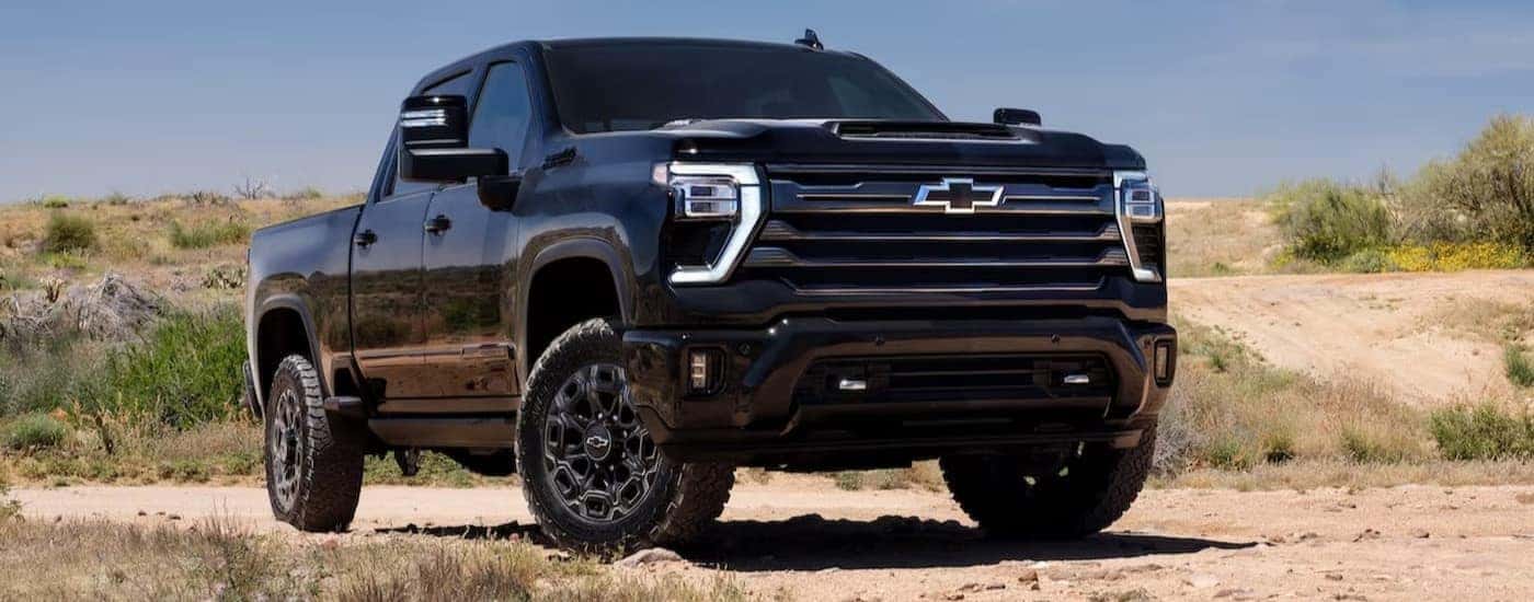 A black 2024 Chevy Silverado 2500 HD Midnight Edition is shown parked off-road.